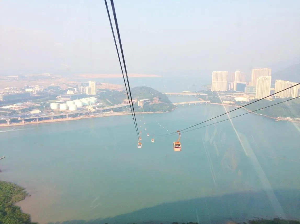 Cáp treo Ngong Ping 360 đang di chuyển qua khu vực biển xanh, kết nối đất liền với làng Ngong Ping
